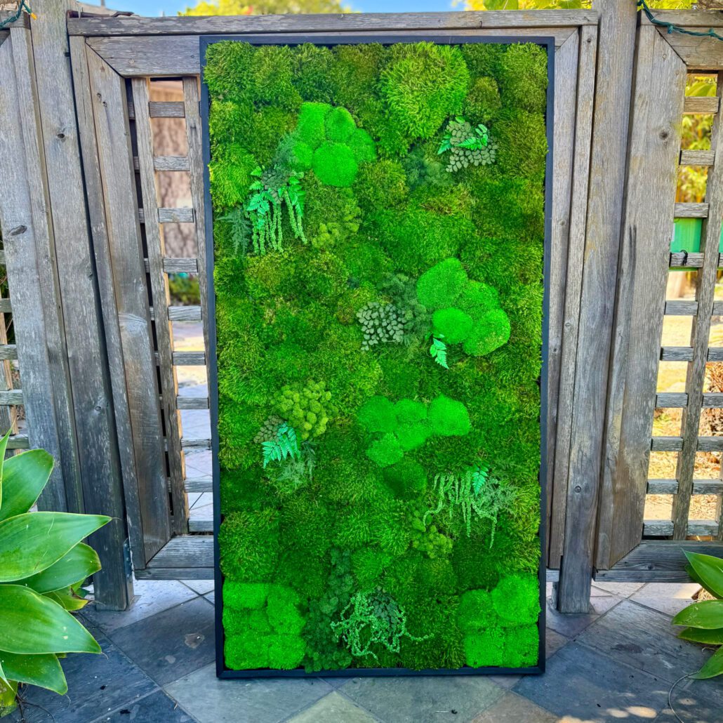 A beautiful moss artwork resting against a gate. for sale.